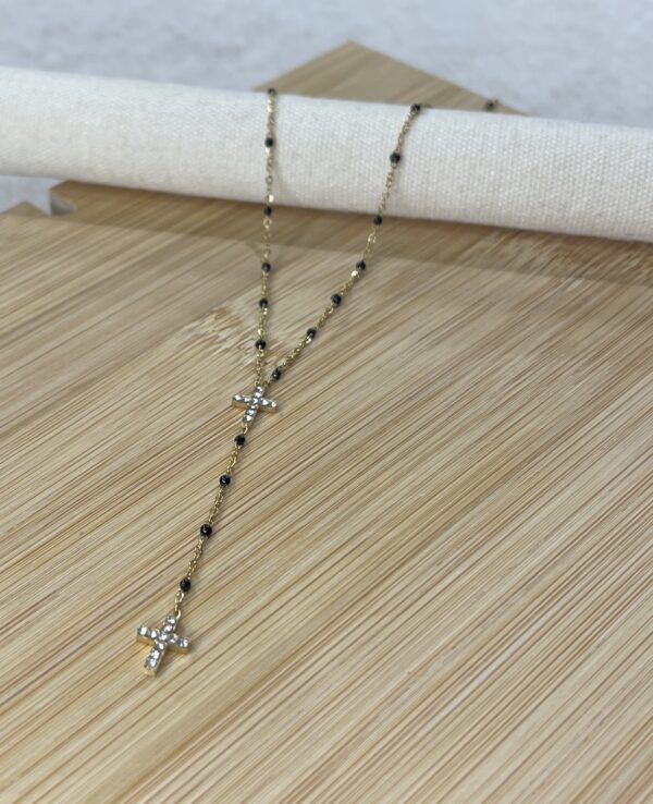 Image d'un collier sautoir croix doré et perles noires de la boutique Erika.